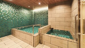 Un área de spa con dos jacuzzis, techo de madera, paredes con azulejos y una barandilla de metal.
