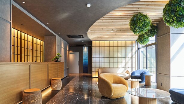 Un vestíbulo moderno con mostrador de recepción, zona de estar y pared de vidrio.