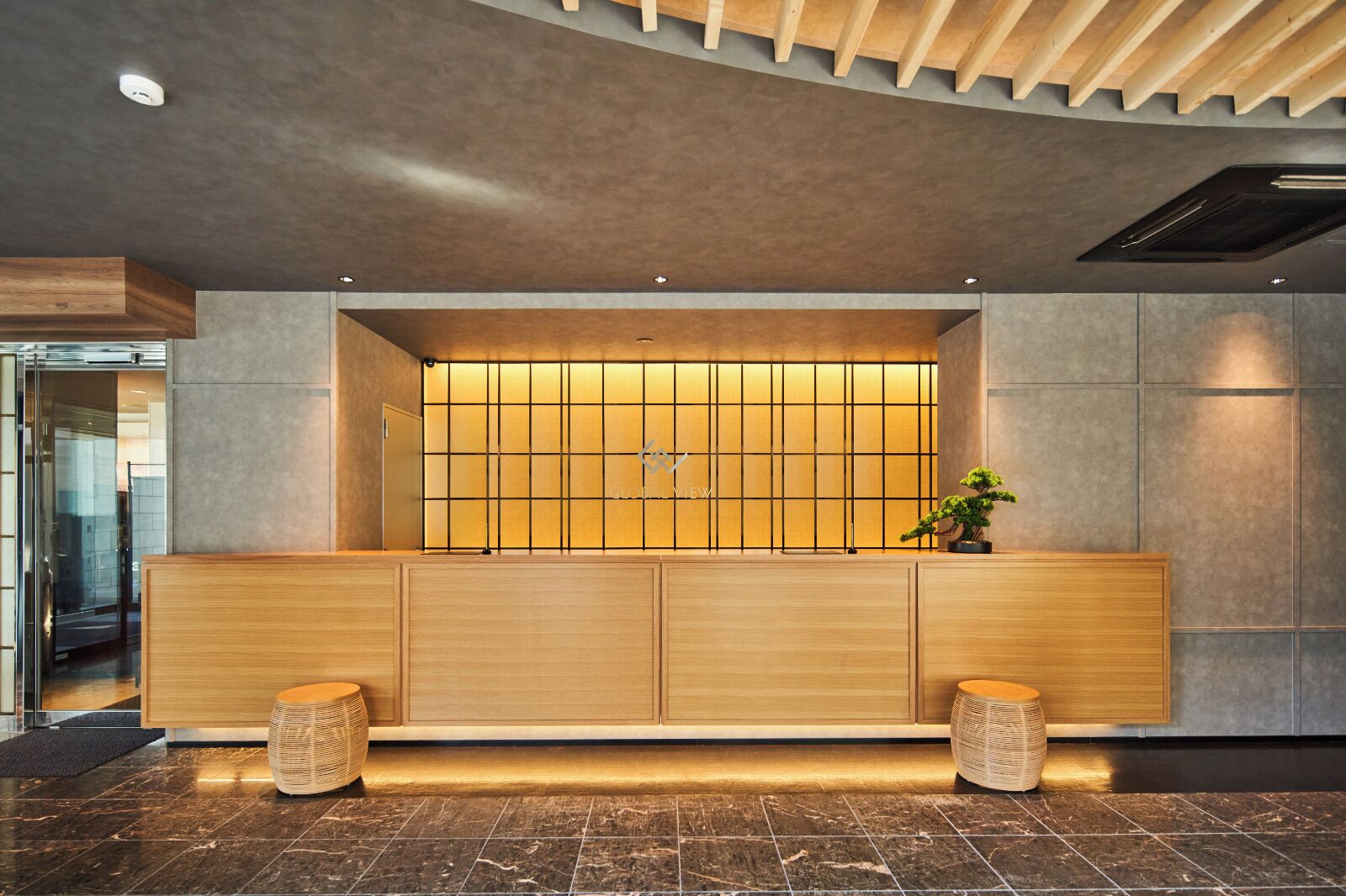 Zona de recepción con un mostrador de madera, una planta en maceta y un diseño moderno de techo.