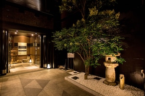 A hotel entrance with a stone lantern, a small tree, and a sign indicating the hotel name. - R&Run Kyoto serviced apartment & suites (Kyoto)