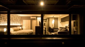 A modern hotel room with a large bed, a desk, and a dining area.
