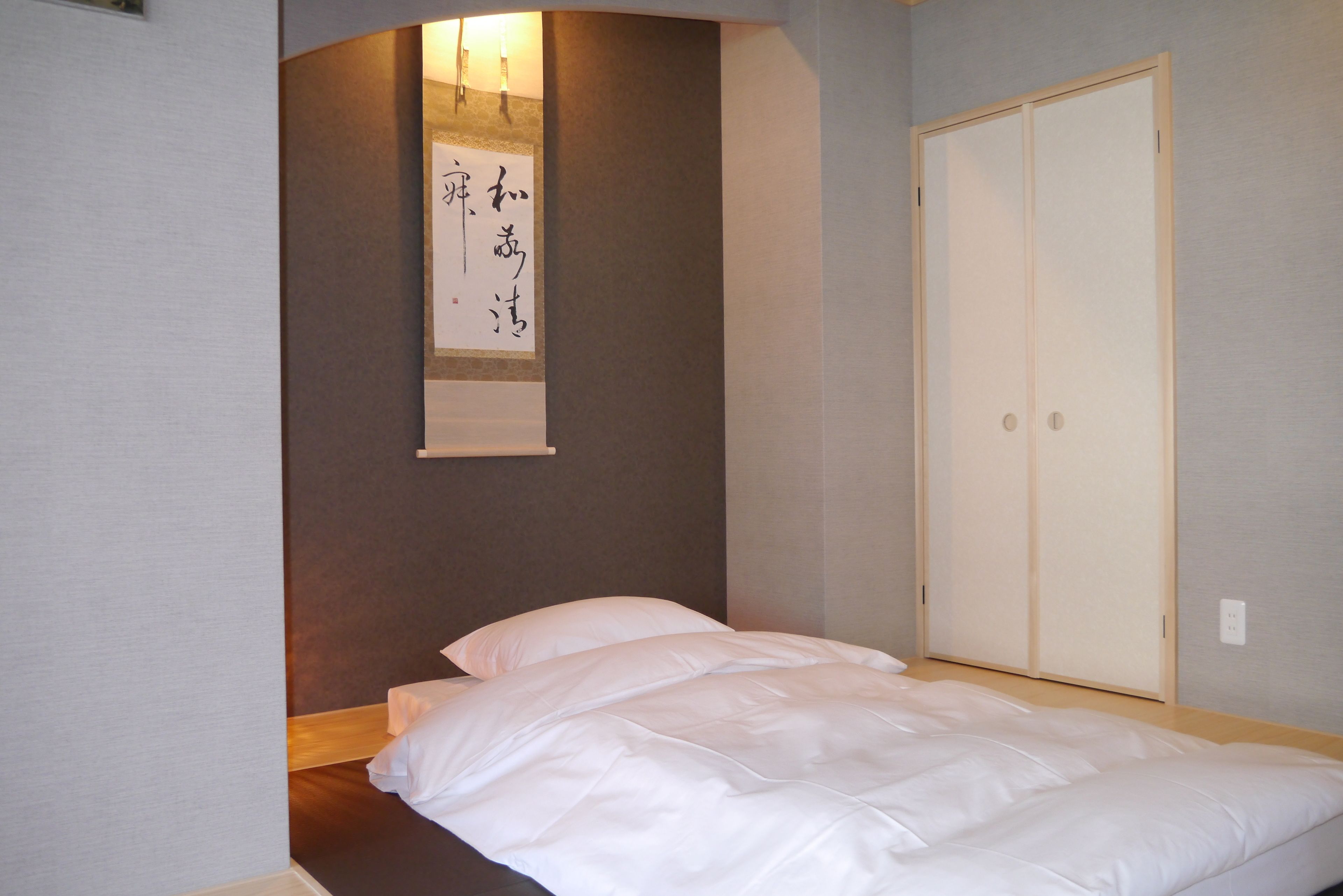 Ein Schlafzimmer mit einem Bett, einem Holzkopfstück, einer Wandleuchte und einer Schiebetür.