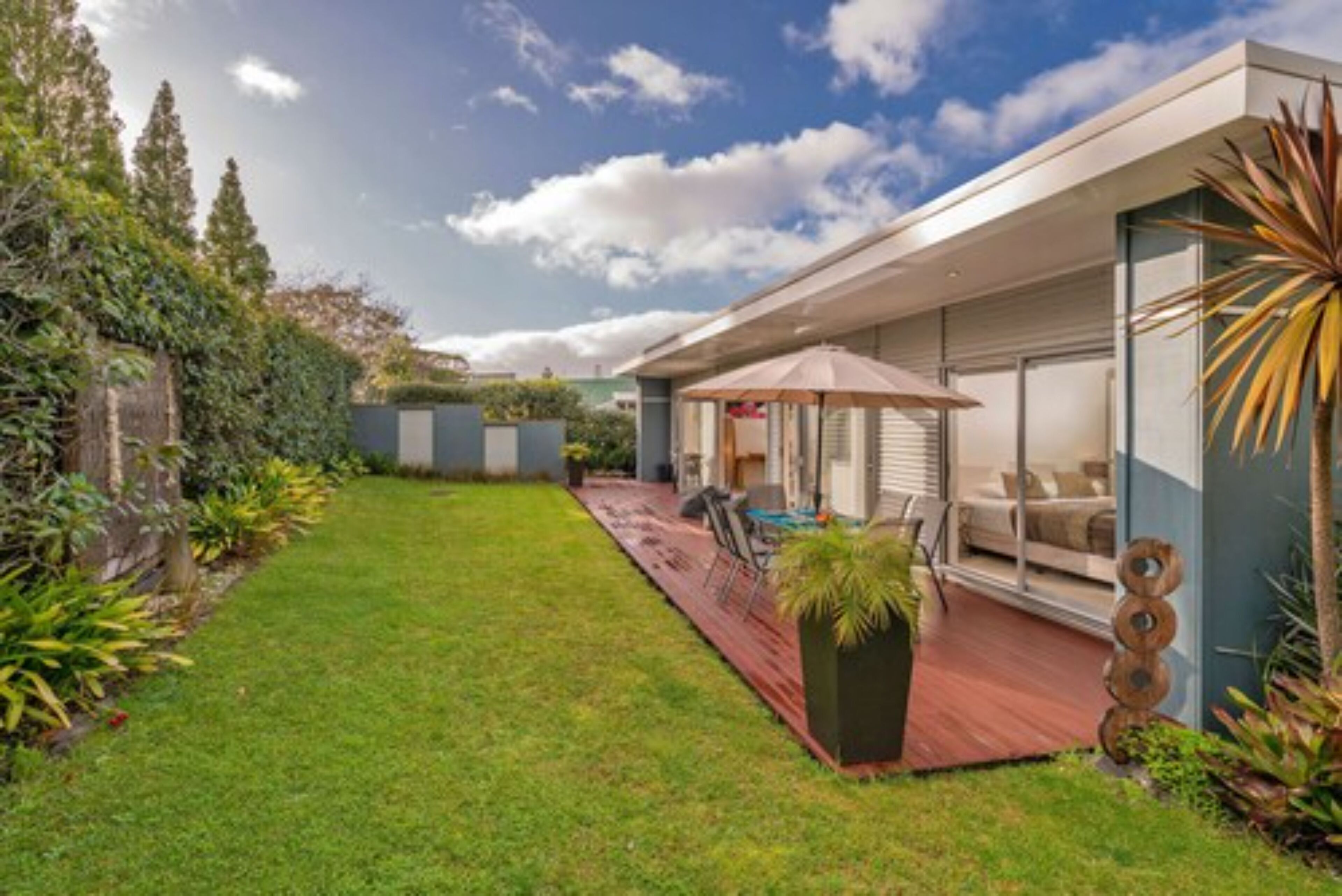 Uma casa moderna com um amplo quintal, um pátio com mobiliário externo e uma grande janela com vista para o jardim.