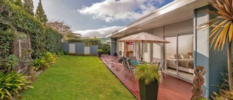 A modern house with a spacious backyard, a patio with outdoor furniture, and a large window overlooking the garden.
