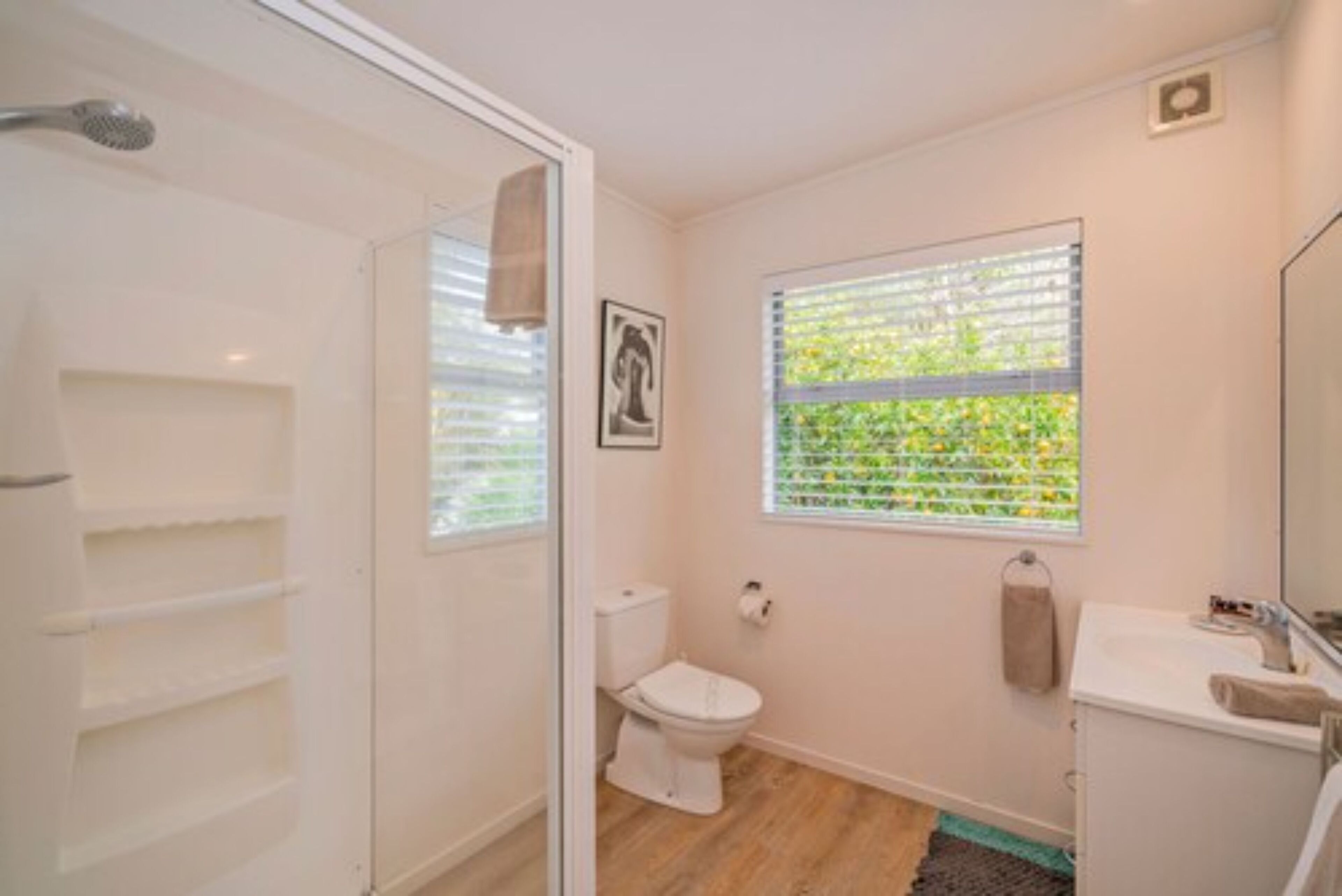 Une salle de bain équipée de toilettes, d’une douche et d’une fenêtre avec des stores.