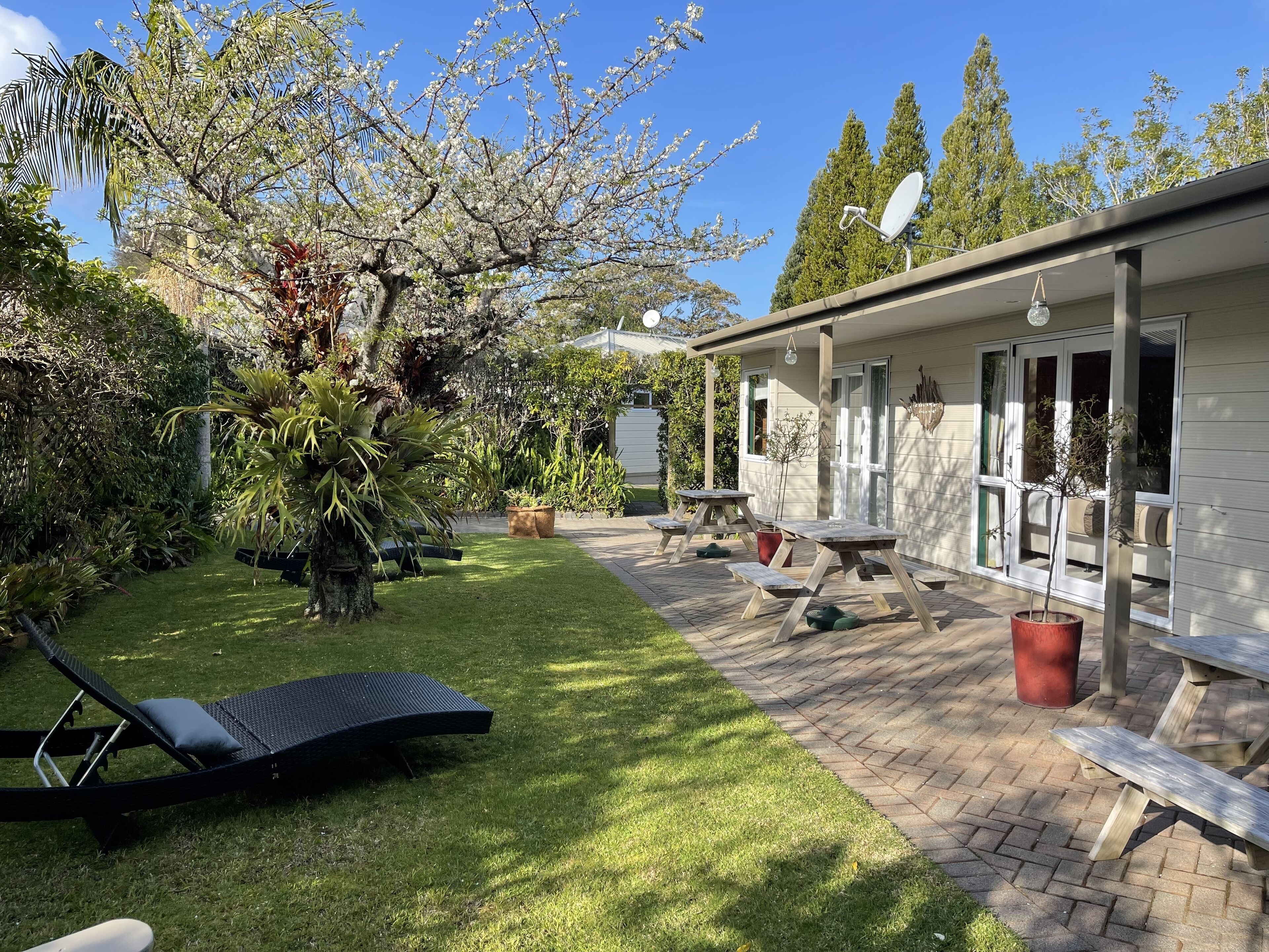 A patio area with a lawn, a lounge chair, and a table with benches.