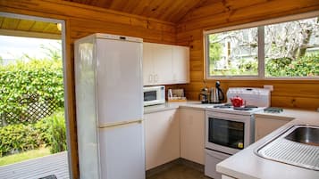 A compact kitchen with a refrigerator, microwave, stove, and sink.
