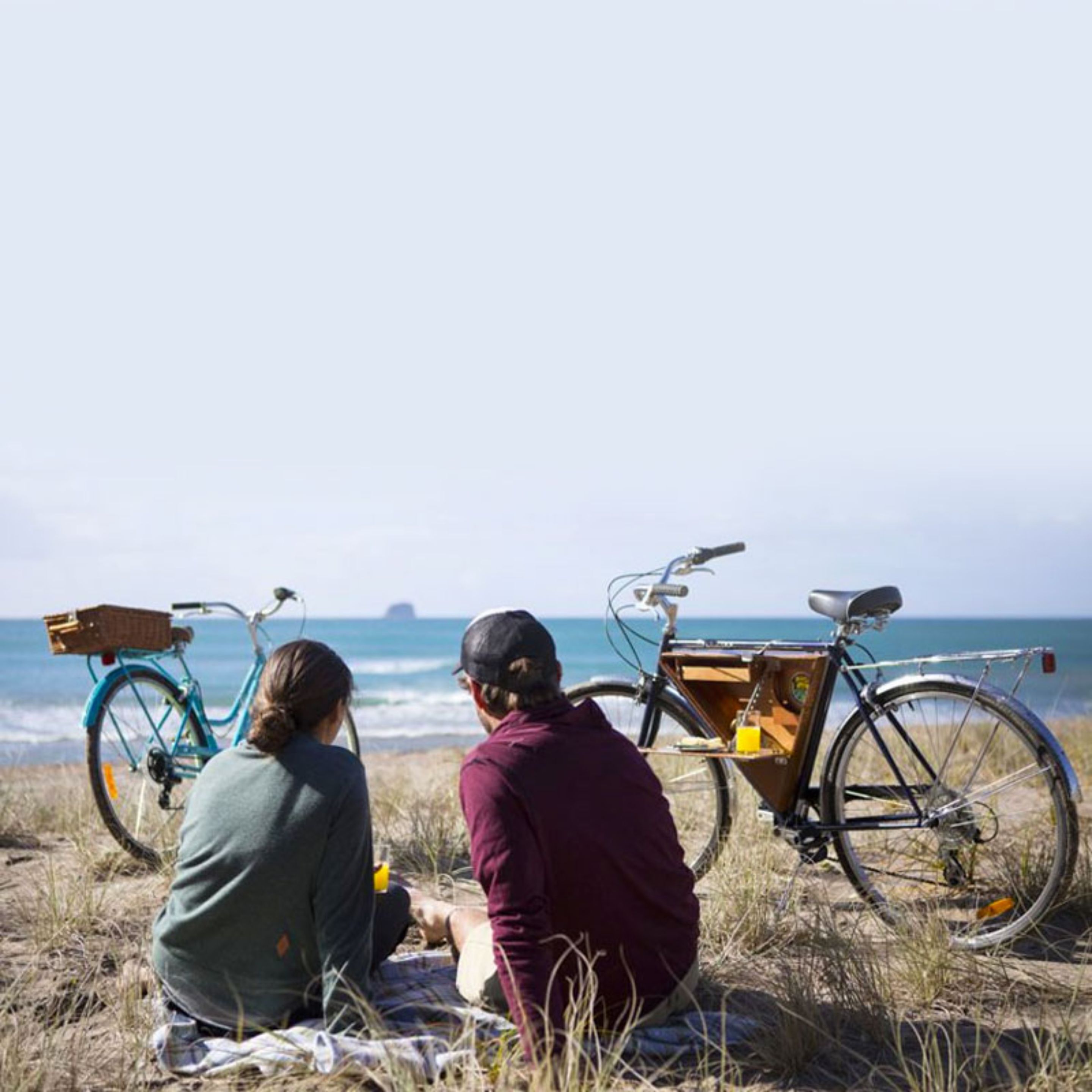Twee personen zitten op het strand met fietsen.