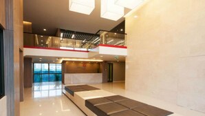 A modern lobby with a glass railing, a reception desk, and a view of the outdoors. - Landmark Residence (Bang Sao Thong)