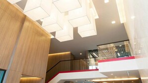 A modern interior with geometric light fixtures, a wooden panel wall, and a glass railing on a balcony. - Landmark Residence (Bang Sao Thong)