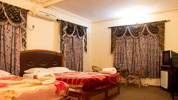 A hotel room with two beds, a small table, a chair, an air conditioner, and a television. - Regal Hetauda Resort Pvt. Ltd. (Hetauda)