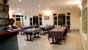 A dining area with multiple tables and chairs, a reception desk, and large windows. - Regal Hetauda Resort Pvt. Ltd. (Hetauda)