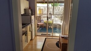 Une cuisine compacte équipée d’un four à micro-ondes, de placards et d’une petite table avec une chaise.