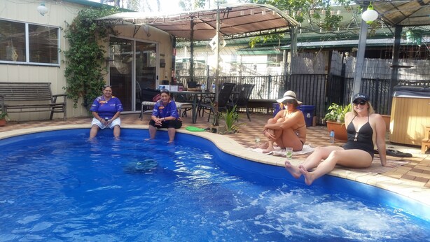 Une piscine avec trois personnes assises au bord.