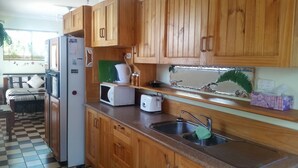 Une cuisine compacte avec des meubles de rangement en bois, un réfrigérateur, un four à micro-ondes, un grille-pain et un évier.