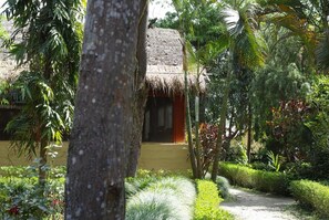 A thatched-roof structure surrounded by lush greenery and a well-maintained garden path. - Forest Hideaway Resort PVT LTD (Bardiya National Park)