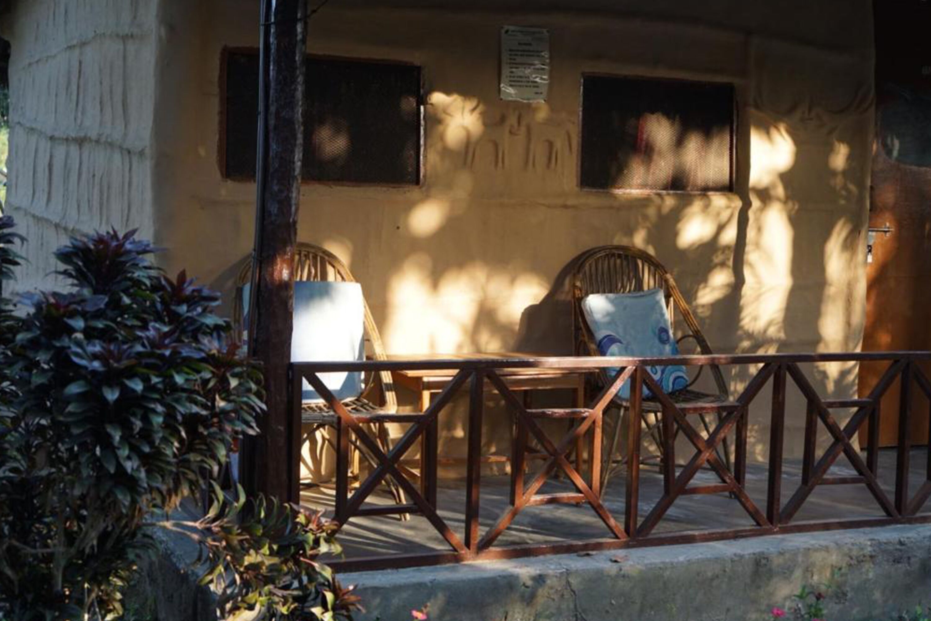 Un espace patio agrémenté d’une rambarde en métal, de deux fauteuils en osier et d’une table.