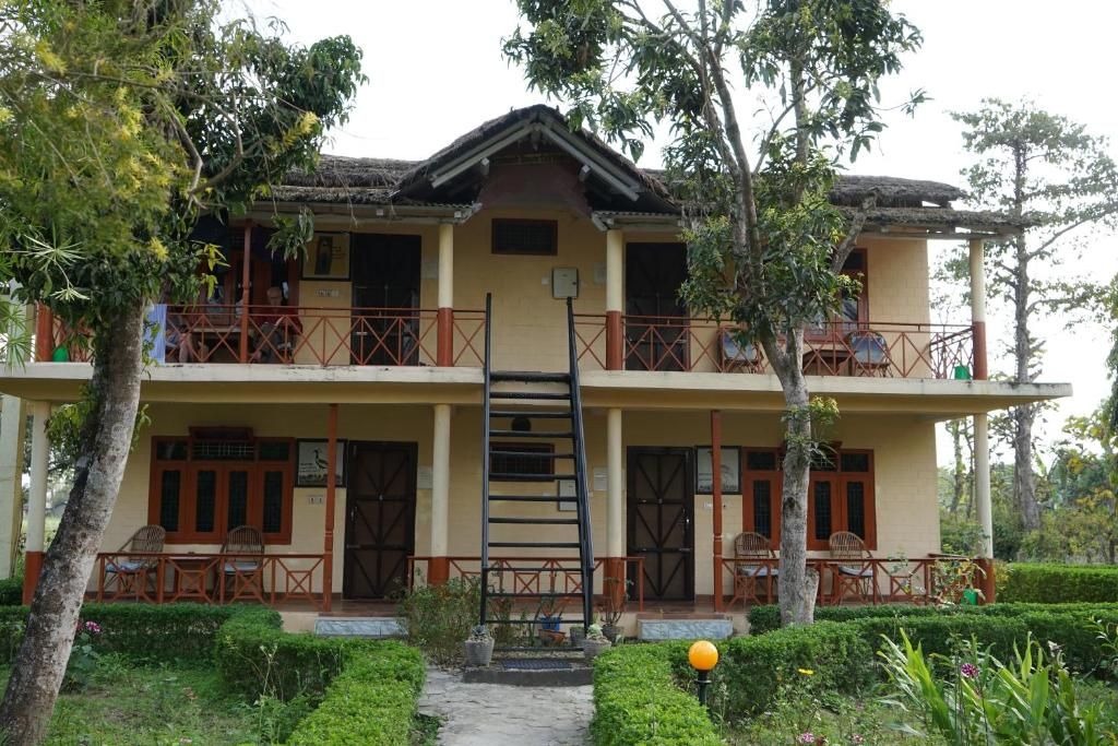 A two-story building with a balcony on the upper floor, a staircase leading to the upper level, and a small garden area in front.