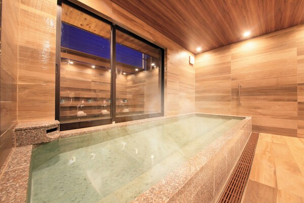 Un moderno spa con una bañera de hidromasaje de cristal, paredes de madera y suelo de baldosas.