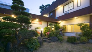 A modern building with a well-maintained garden featuring various plants and rocks. - Tamagawa Ryokan (Tahara)