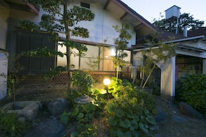 A residential garden with a well-maintained lawn, a variety of plants, and a stone pathway. - Tamagawa Ryokan (Tahara)