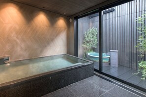 Un baño moderno con una bañera independiente, un ventanal grande y una planta en maceta.