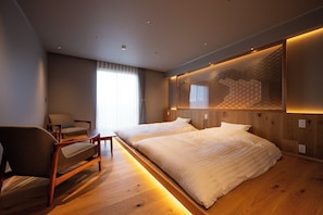 A modern hotel room with a wooden floor, a large bed, a desk with a chair, and a large window with curtains. - Tamagawa Ryokan (Tahara)