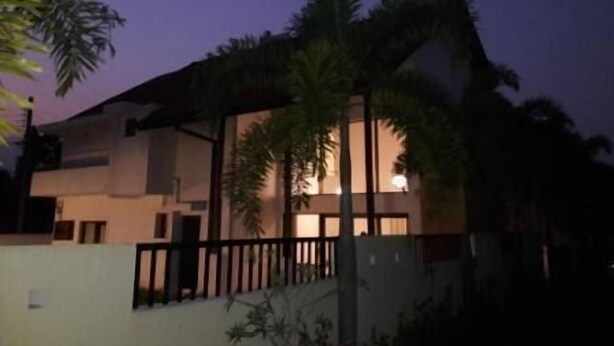 Um edifício de dois andares com uma varanda, rodeado por palmeiras.