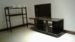 Um móvel para televisão com uma TV de tela plana, uma mesa pequena e uma estante de metal.