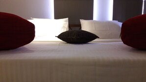 Quarto de hotel com cama, almofadas e janela.