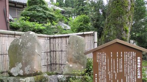 Ein Steinweg führt zu einem traditionellen japanischen Gebäude mit einem hölzernen Zaun und einem Schild.