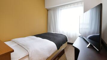 Ein Hotelzimmer mit Bett, Fernseher und einem Vorhangfenster.
