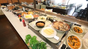Ein Buffet mit verschiedenen Speisen, darunter Salate, Fleischgerichte und Desserts.