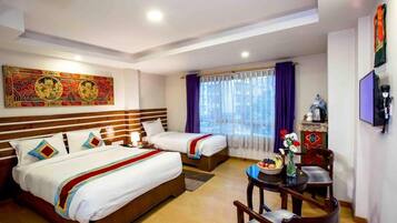 A hotel room with two beds, a dining table with chairs, a coffee machine, and a decorative vase.