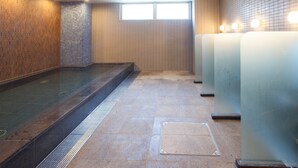 Une salle de bain moderne avec une douche à parois de verre, des murs carrelés et une fenêtre laissant entrer la lumière naturelle.