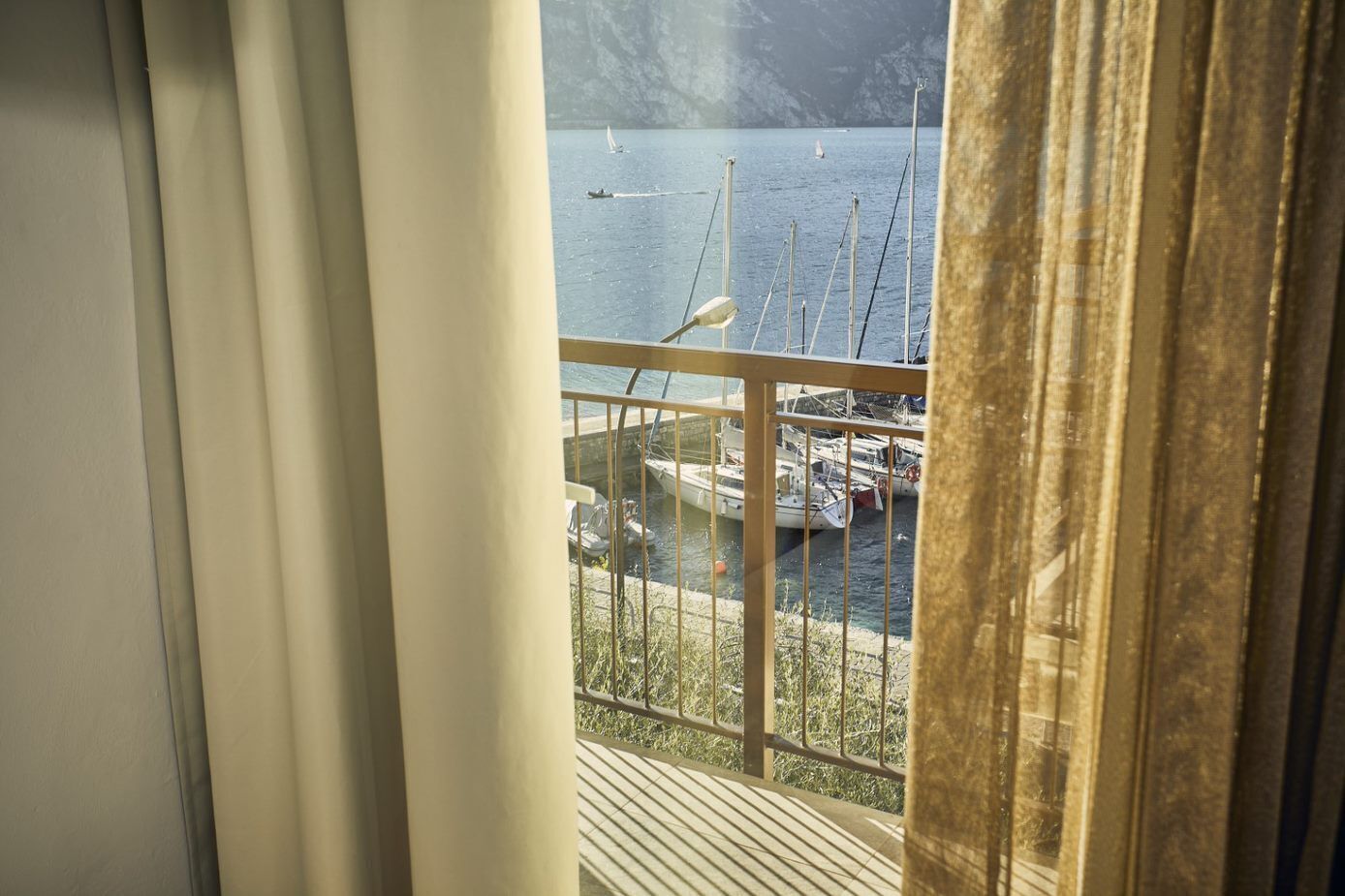 Un balcón con vista a barcos y un paisaje montañoso.