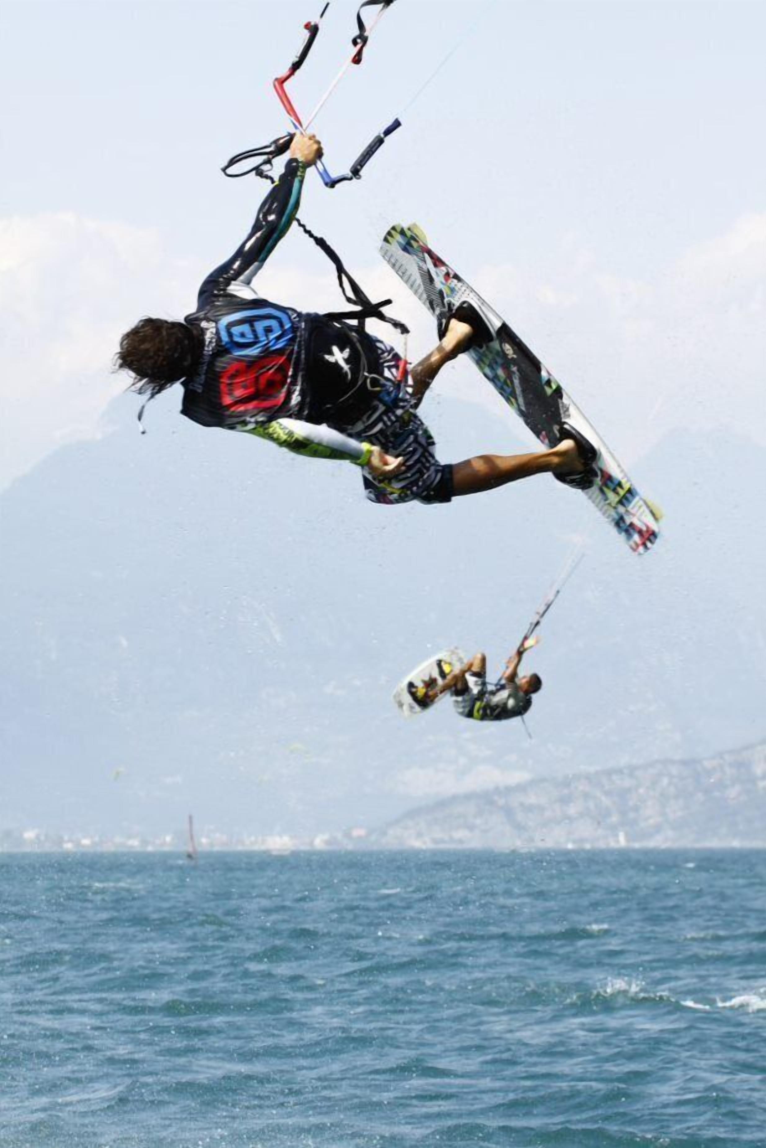Una persona fa kitesurf sull'acqua, con un ponte sullo sfondo.