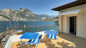 A balcony with two blue sun loungers, a view of the sea, and a mountainous backdrop. - Hotel Paradiso (Nago-Torbole)