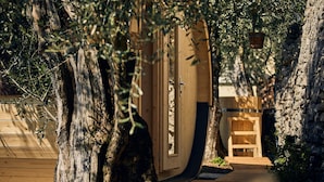 A wooden building with a door, surrounded by trees and a stone wall. - Hotel Paradiso (Nago-Torbole)