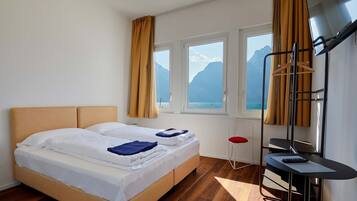 A hotel room with a bed, a desk, and a view of mountains through the windows.