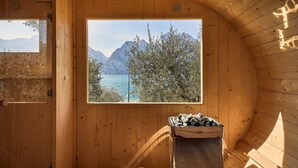 A wooden cabin with a large window overlooking a lake and mountains. - Hotel Paradiso (Nago-Torbole)