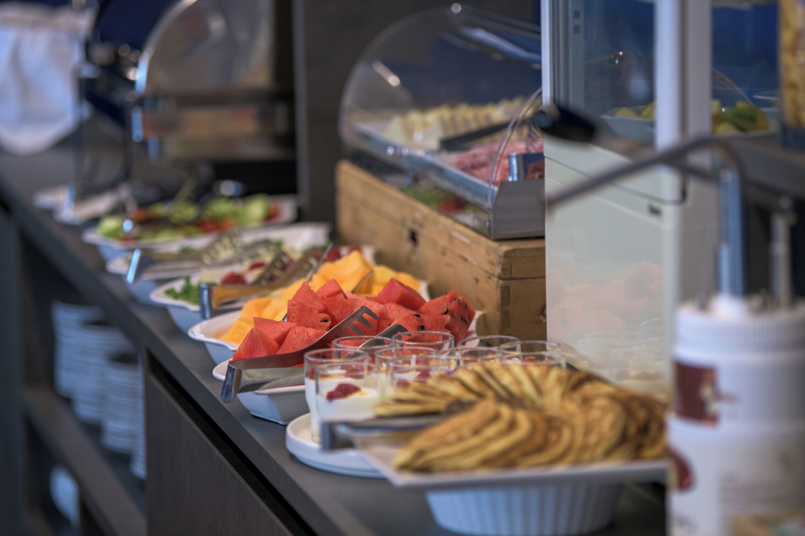 Un bufé con diferentes opciones de comida, incluyendo frutas, pasteles y bebidas.
