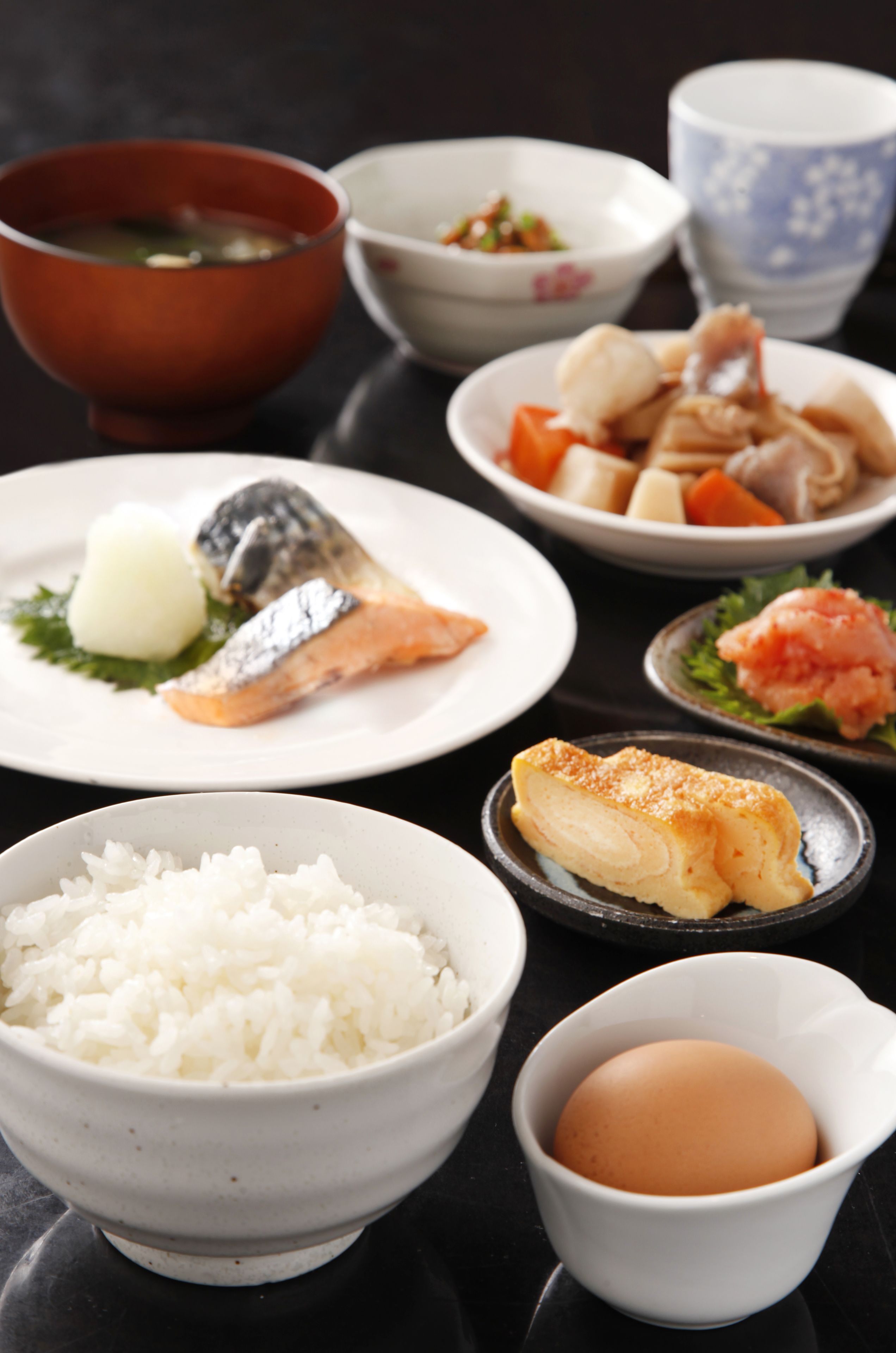 A variety of dishes including rice, fish, and vegetables on a table.
