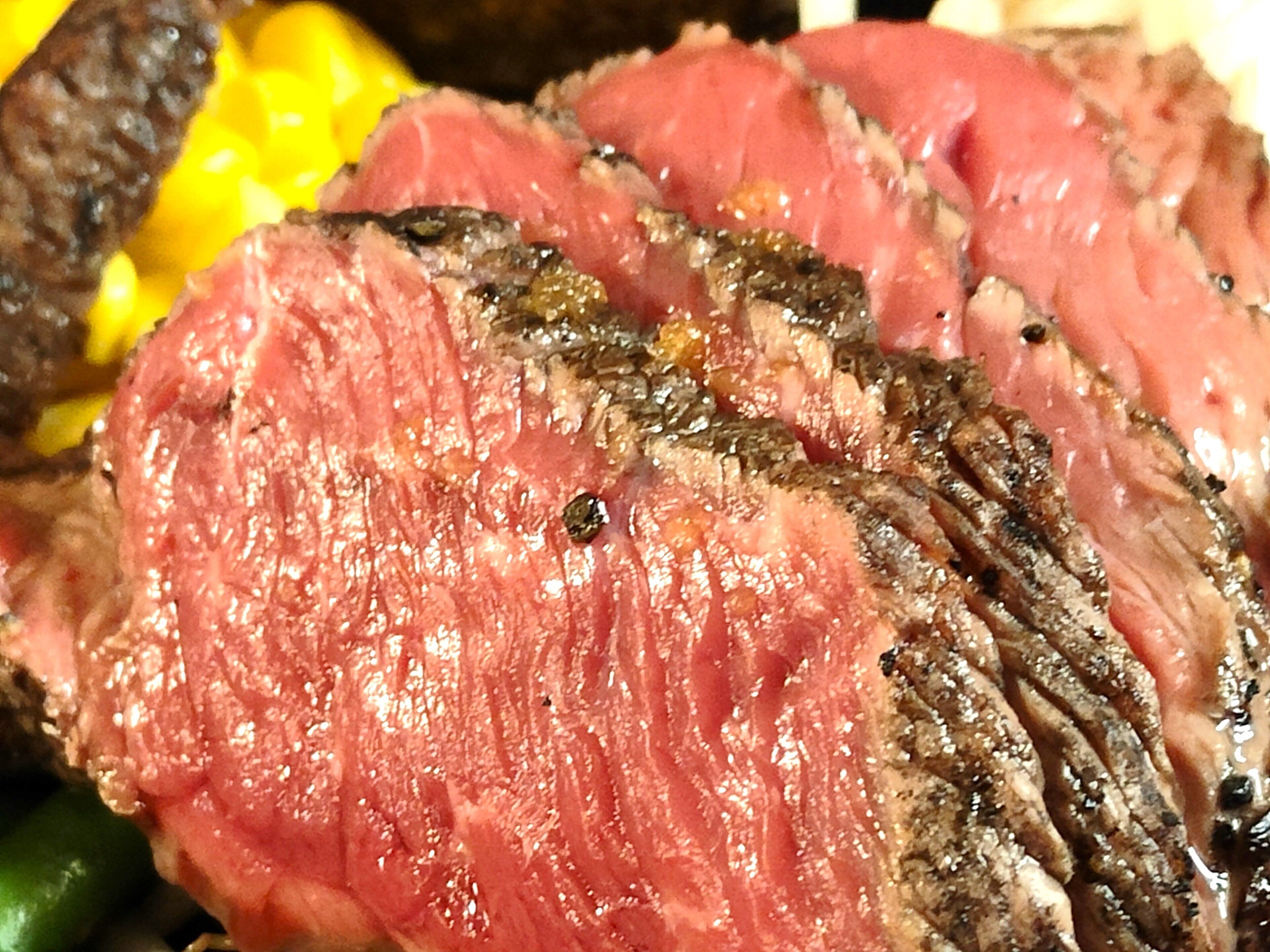 A close-up of a cooked steak with visible grill marks and a pink center, indicating it is medium-rare.