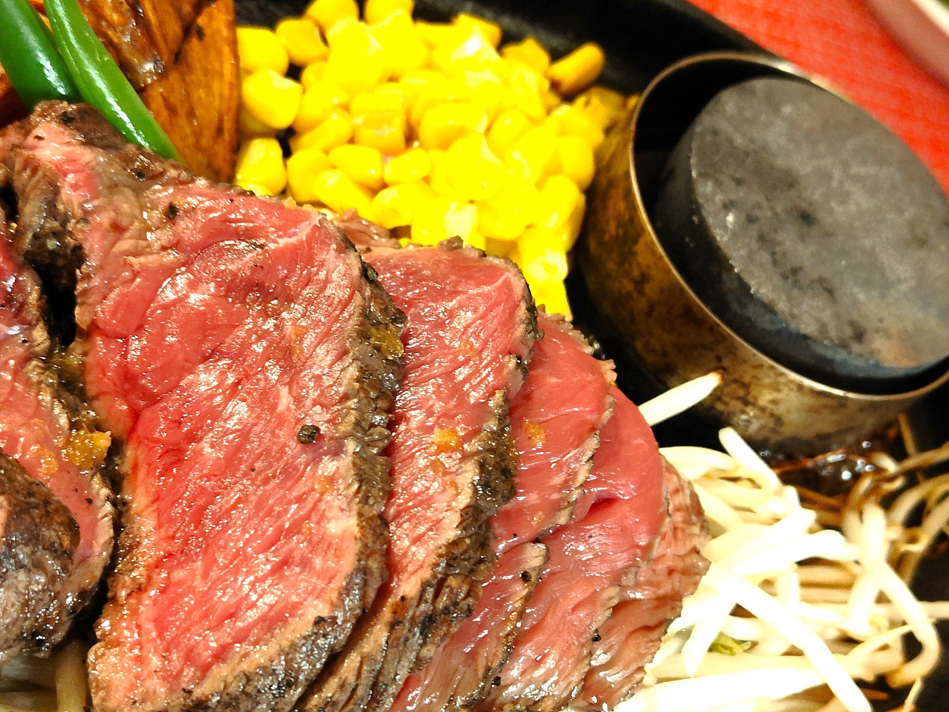 A close-up of a steak with corn and a pot.