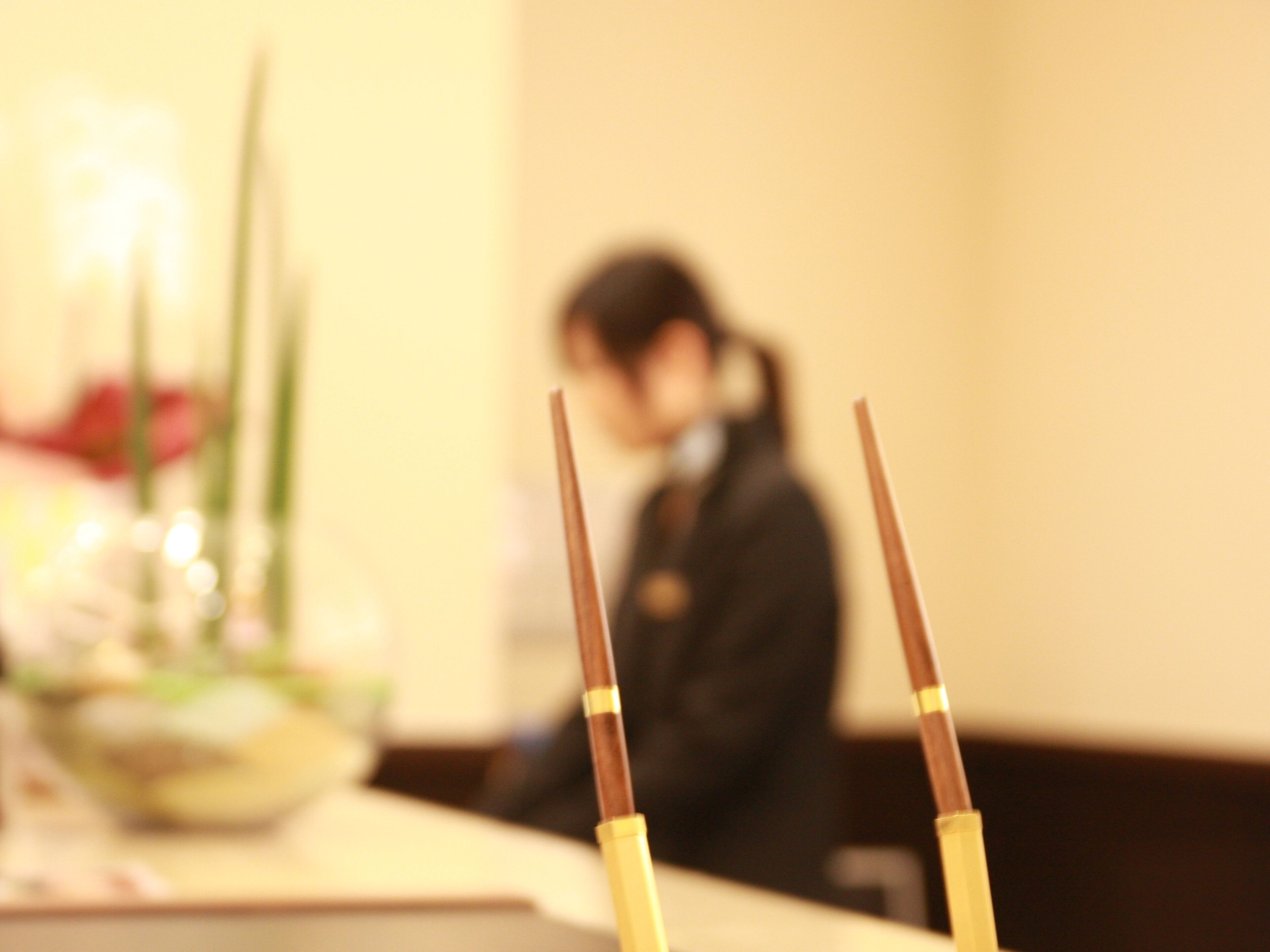 A dining table with chopsticks and a blurred background of a person.