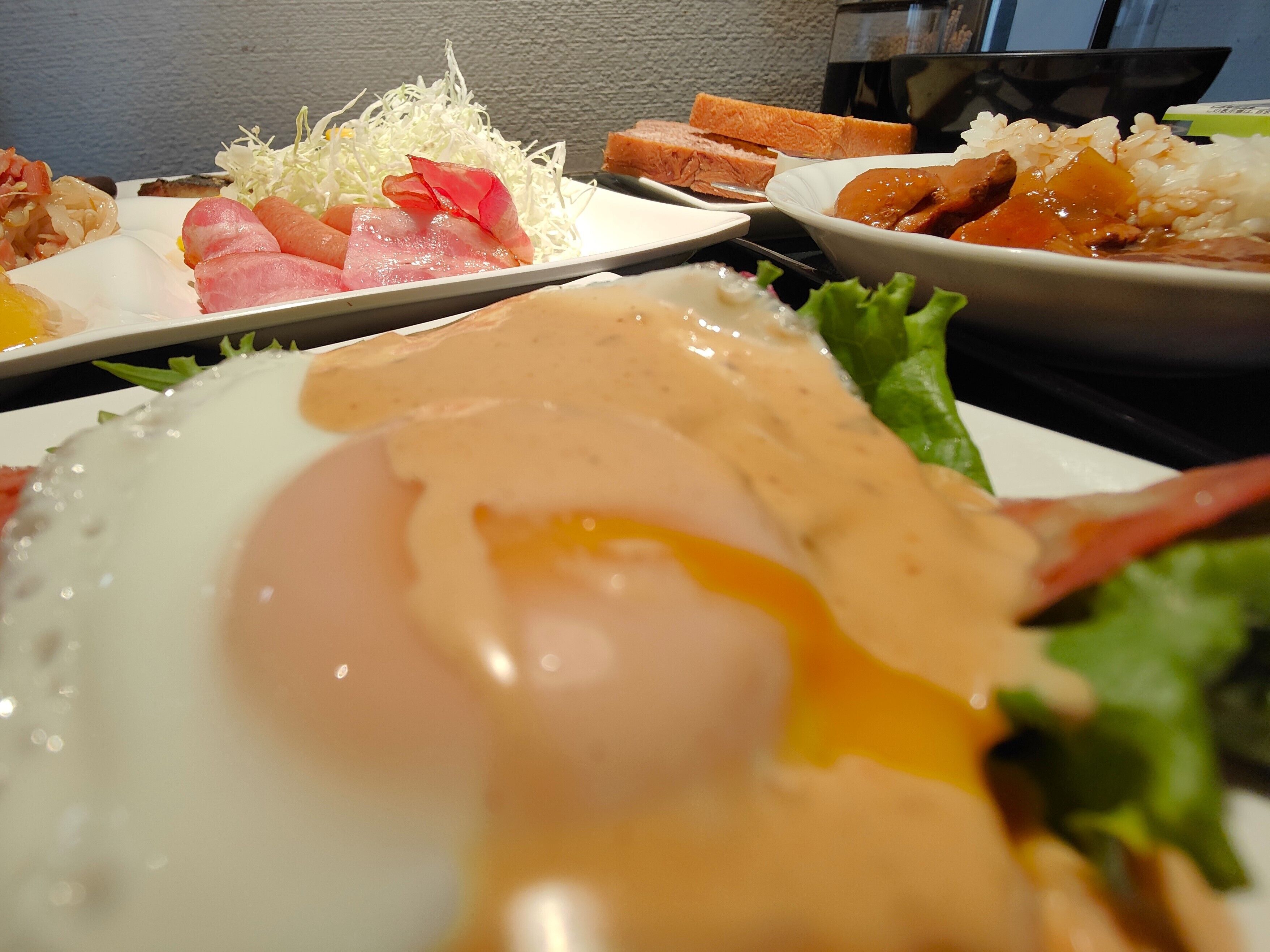 A meal with various dishes including a fried egg, sashimi, rice, and vegetables.