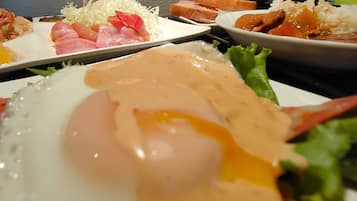 A meal with various dishes including a fried egg, sashimi, rice, and vegetables.