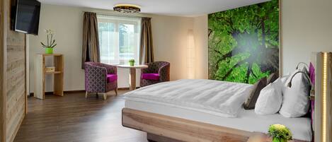 A hotel room with a bed, a chair, a table, a TV, and a large window with curtains.