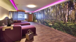 Una habitación de hotel moderna con un mural de un gran bosque, una zona de estar con una mesita de bandeja y suelo de madera.